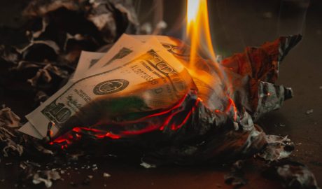 $100 bills on fire with ashes