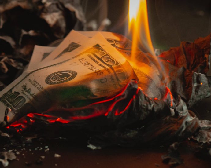 $100 bills on fire with ashes