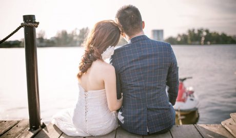 newlyweds sitting on dock overlooking bay