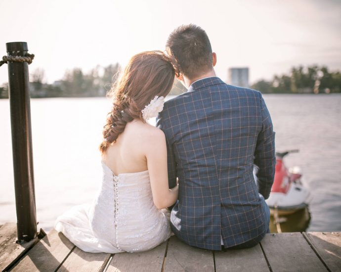 newlyweds sitting on dock overlooking bay