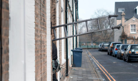 Man carrying ladder into building