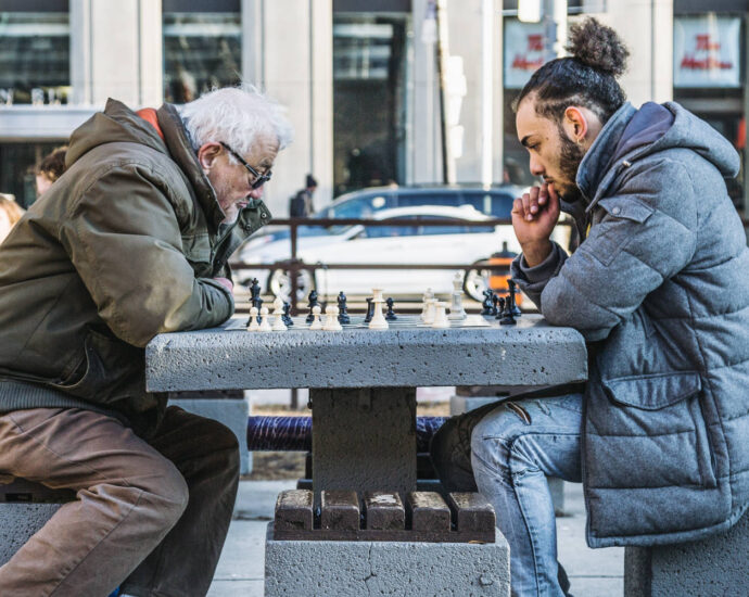 young man and older man playing chess in ourdoor park