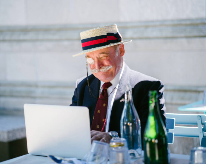 older man in hat and monocle at outdoor cafe