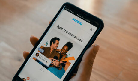 person holding phone with Venmo homepage showing