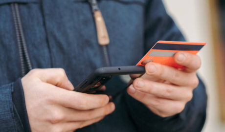 man holding credit card typing on cell phone