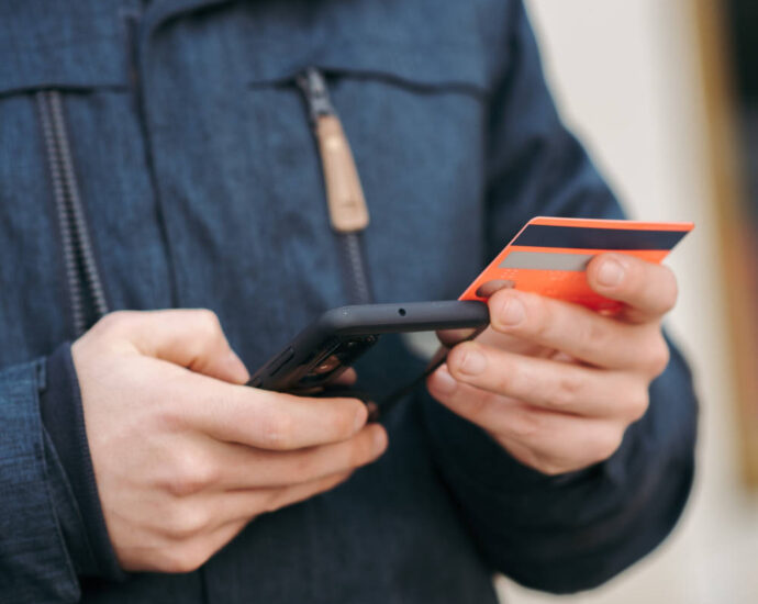 man holding credit card typing on cell phone