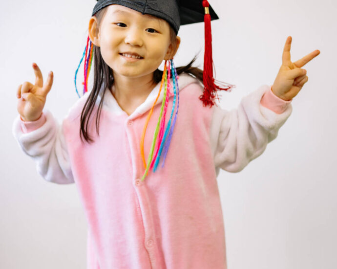 Asian girl in pink pjs wearing mortar board graduation cap