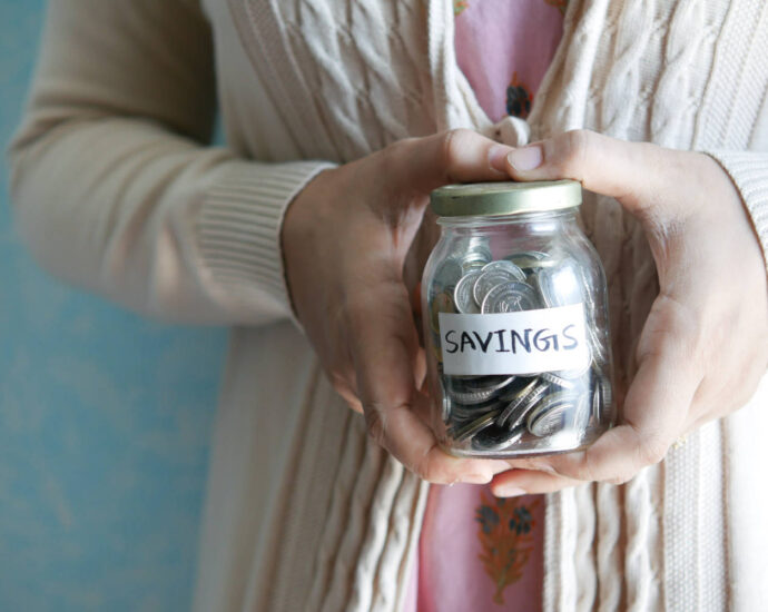 woman holding jar labeled "savings" with coins inside