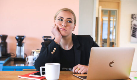 blond woman looking bored with open laptop