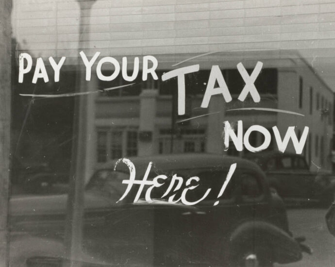 Vintage BW Image of store front with words "Pay Your Tax Now Here!"