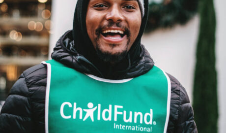 Man in green vest with words "ChildFund International" on it