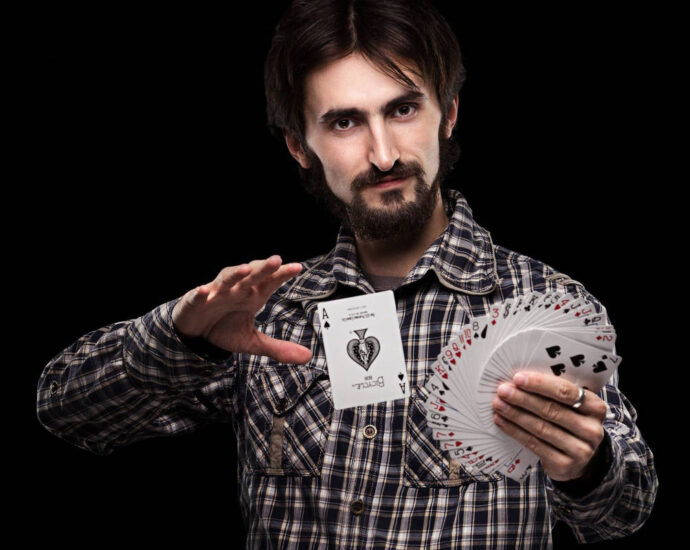 man holding fanned deck of cards with ace of spades floating beside