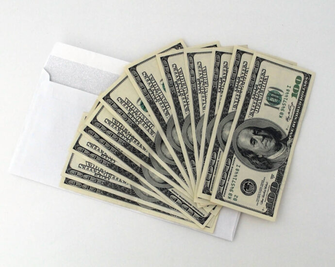 $100 bills fanned out on top of white envelope