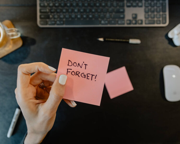 hand holding post it note saying "Don't Forget"