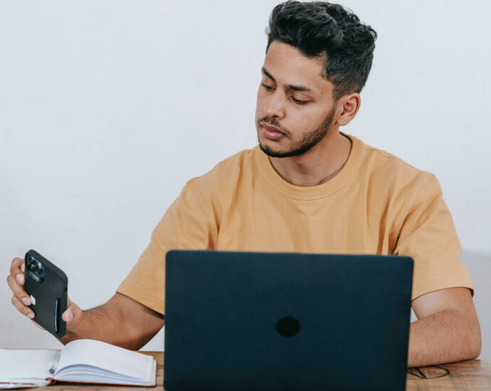 man checking cellphone while on laptop