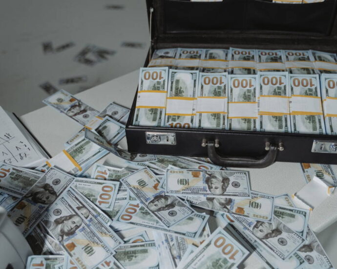 briefcase full of cash with more piled in front