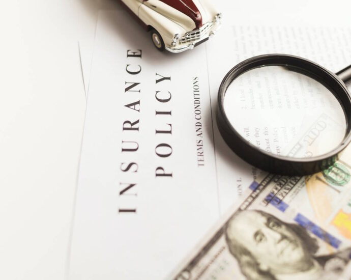 insurance policy with model car, magnifying glass, and $100 bill