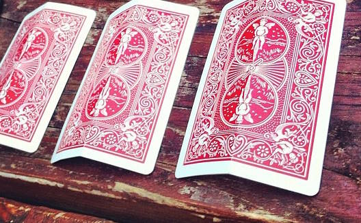 three folded cards turned down on a table a la three card monte