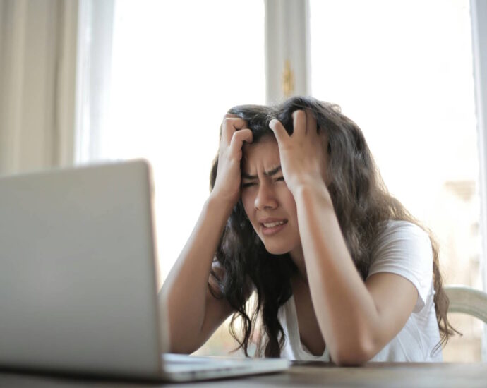 young woman looking frustrated at her laptop computer